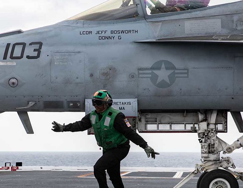 La contramaestre de aviación (equipo) de tercera clase Lacarsha Mitchell, de Chicago, asignada al portaaviones USS Gerald R. Ford (CVN 78), barre la cubierta mientras un F/A-18E Super Hornet adscrito a los "Ragin' Bulls" del Escuadrón de Cazas de Ataque (VFA) 37 se prepara para despegar desde la cubierta de vuelo durante las operaciones de vuelo, el 23 de marzo de 2022. El Gerald R. Ford se encuentra en el Océano Atlántico llevando a cabo la certificación de la cubierta de vuelo y las calificaciones del ala aérea del portaaviones como parte de la fase básica adaptada del buque antes del despliegue operativo. Foto de la Armada de EE.UU. por el especialista en comunicación de segunda clase Zachary Melvin