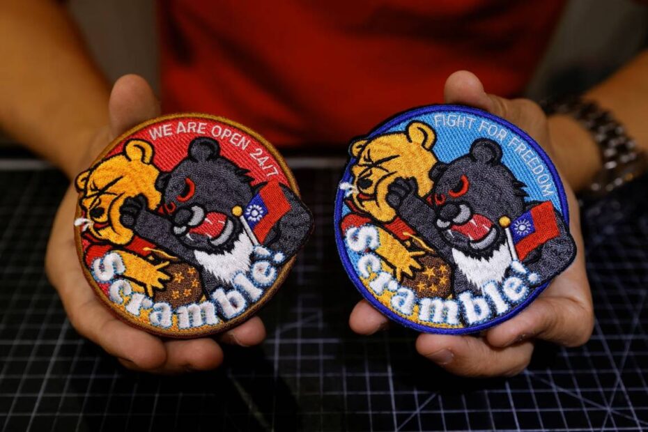 Alec Hsu muestra a la cámara unos parches en los que aparece un oso negro de Formosa sosteniendo la bandera de Taiwán y dando un puñetazo a Winnie the Pooh en su tienda de Taoyuan, Taiwán 10 de abril de 2023. REUTERS/Carlos García Rawlins