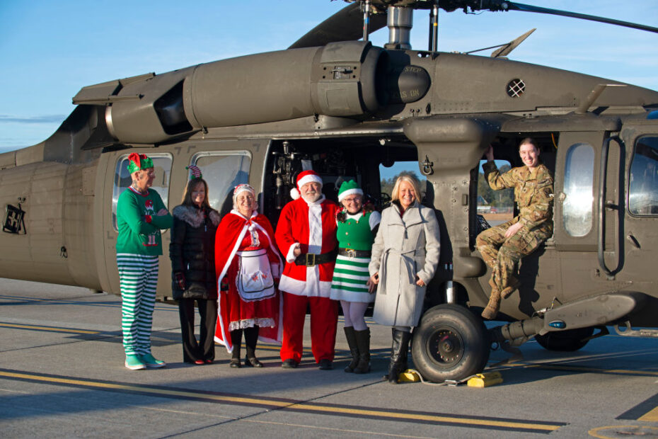 De derecha a izquierda, la sargento Audrey Monroe, jefe de tripulación de la Compañía A, 1-169º de Aviación, de la Guardia Nacional del Ejército de New Hampshire, se une a Christine McManus y a voluntarios de la Asociación de Empleados Estatales de N.H. en la línea de vuelo con un helicóptero Black Hawk cargado de regalos de Navidad donados el 12 de diciembre de 2023, en las Instalaciones de Apoyo a la Aviación del Ejército en Concord. Los guardias se unieron a los voluntarios de la SEA en la Operación Papá Noel para entregar regalos a las familias necesitadas de todo el Estado de Granito. Foto del Sargento Mayor Charles Johnston, NHNG Deputy State PAO. Foto de la ANG por el Sargento Mayor Charles Johnston