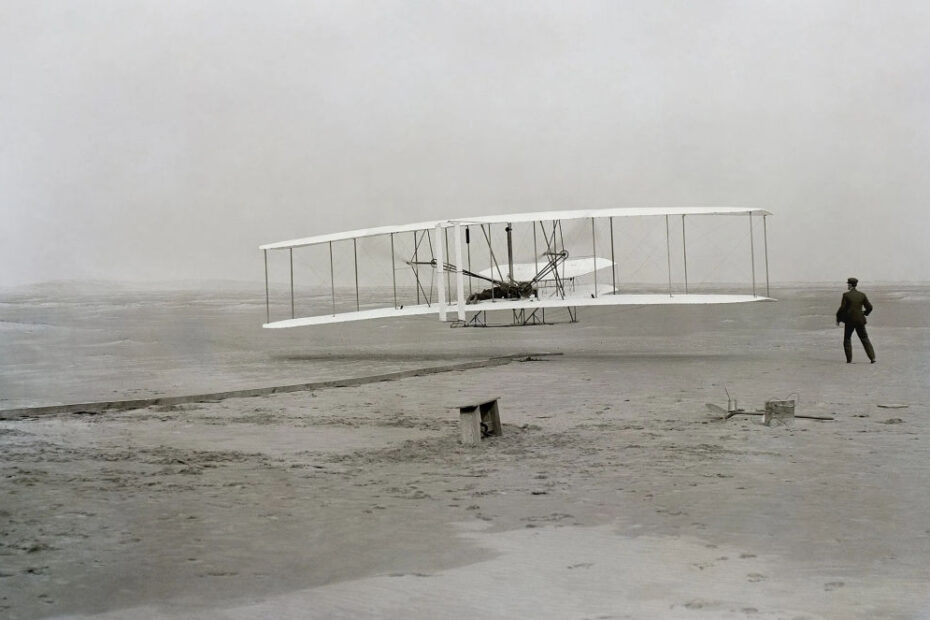 Orville Wright durante el primer vuelo propulsado de un avión más pesado que el aire; Wilbur está de pie a la derecha del avión. Crédito de la imagen: cortesía del Servicio de Parques Nacionales de Estados Unidos.