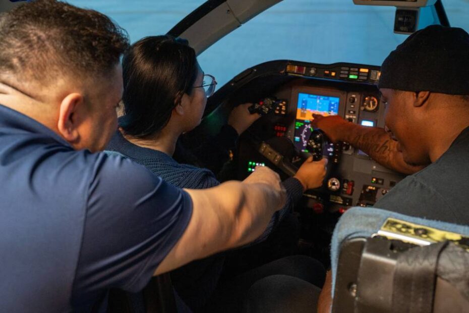 El Coronel retirado Andy Katz señala los instrumentos en la cabina de un simulador del T-1A Jayhawk en la Base de la Fuerza Aérea de Laughlin, Texas, el 17 de diciembre de 2024. Para honrar el legado del T-1A Jayhawk, los aviadores participaron en simuladores de alfombra roja, pudiendo practicar el vuelo del T-1A. (Foto de la Fuerza Aérea de EE.UU. por el sargento Nicholas Larsen)