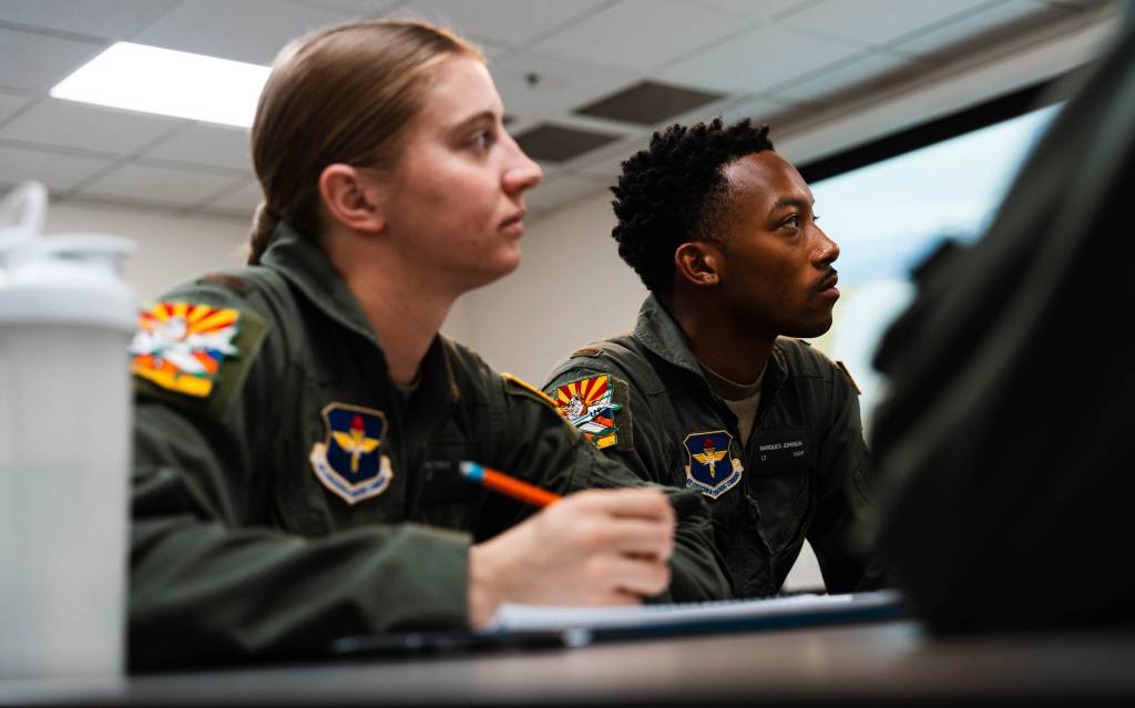 La Subteniente Victoria Cutt y el Subteniente Marques Johnson, estudiantes pilotos de la Fundación Aeroespacial de la Universidad de Dakota del Norte, escuchan a su instructor, el 7 de enero de 2025, en Mesa, Arizona. Los alumnos pilotos están en proceso de obtener sus certificados de piloto privado y sus habilitaciones de vuelo instrumental y multimotor, como parte de las pruebas de grupos pequeños de formación inicial de pilotos del Mando de Educación y Formación Aérea. El AETC está colaborando con el sector de la aviación civil como parte de su plan para revisar la formación de pilotos de la Fuerza Aérea de EE.UU. y de los países asociados. (Foto de la Fuerza Aérea de EE.UU. por el aviador Mason Hargrove)