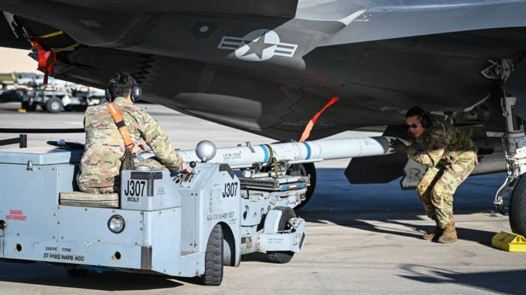 Aviadores estadounidenses asignados al 59º Escuadrón de Pruebas y Evaluación y al 57º Grupo de Mantenimiento transportan un misil aire-aire avanzado de alcance medio AIM-120 en la Base de la Fuerza Aérea de EE.UU. en Nellis, Nevada. La munición fue cargada en un F-35A Lightning II mientras es reabastecido simultáneamente como parte de un evento de prueba de giro de combate integrado. (Foto de la Fuerza Aérea de EE.UU. por la Teniente 1ª Rebecca Abordo)