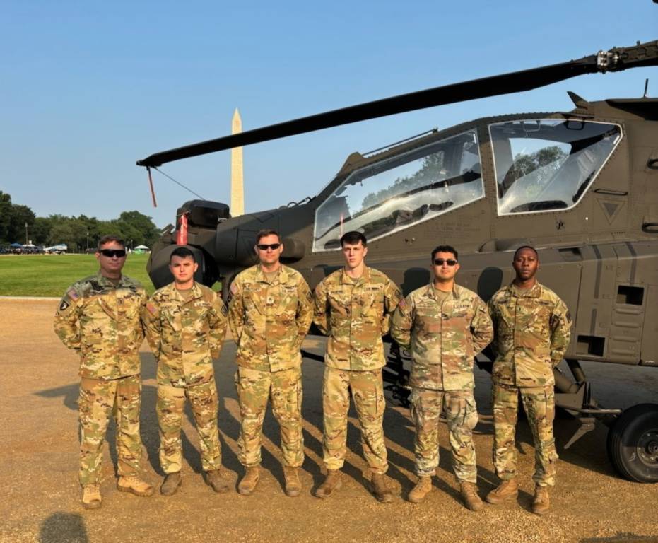 El Suboficial Jefe 4 del Ejército James «Woody» C. Watkins Jr. (izquierda), el Sargento del Ejército Elijah C. Braddy, el Sargento del Ejército Michael A. Frutchey, el Sargento del Ejército Daniel S. Browning Jr., el Sargento del Ejército Edgar Echeverría-Nolasco y el Suboficial Jefe 3 del Ejército Darius T. Jenkins, todos ellos asignados a la Guardia Nacional del Ejército de Carolina del Norte, frente a un AH-64 Apache aparcado en el National Mall de Washington, el 10 de junio de 2025. Los soldados participarán en la celebración del 250 aniversario del Ejército, el 14 de junio de 2025.