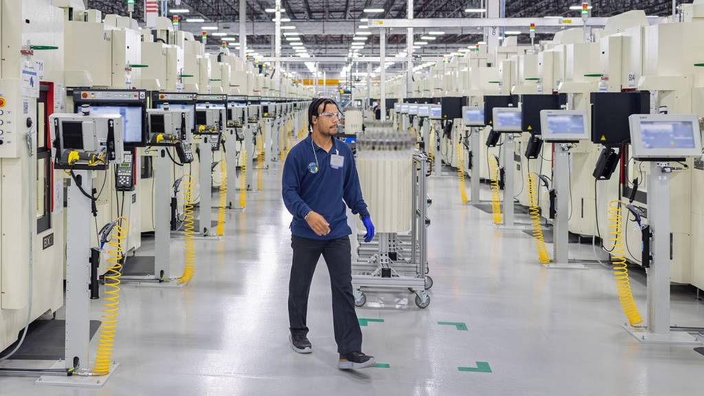 Un operario de la planta de fabricación de álabes y palas de Pratt & Whitney en Asheville, Carolina del Norte, recorre la sección de la obra denominada Taladradora para comprobar el estado de una pieza. Este proceso altamente automatizado permite que una o dos personas gestionen las operaciones de varias máquinas. Algunas partes de esta imagen se han difuminado para proteger información sensible. ©RTX