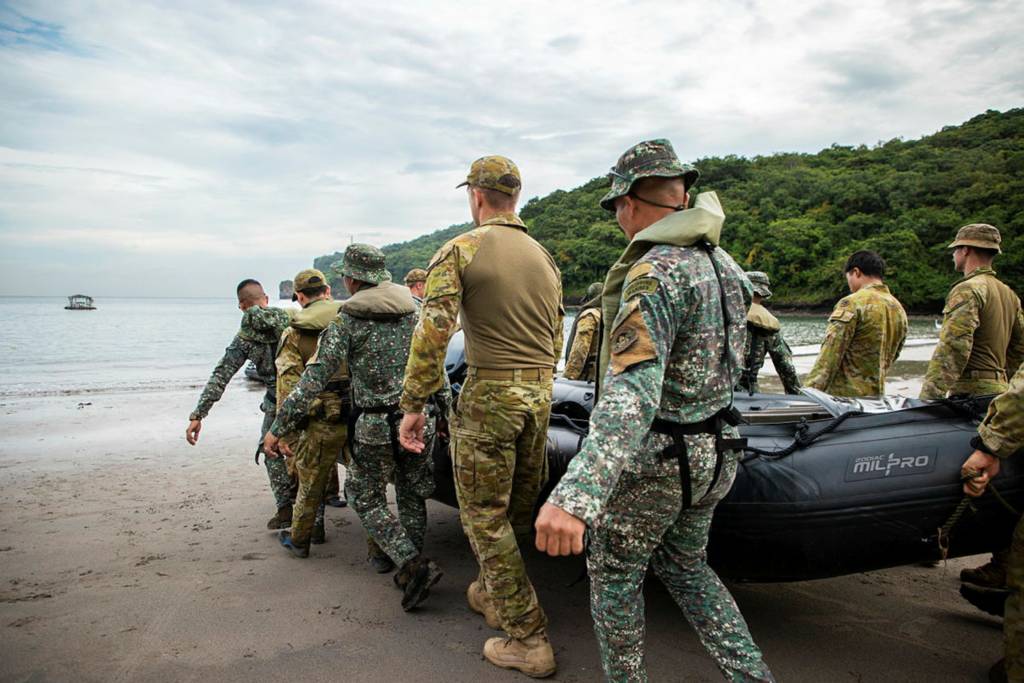Soldados del Ejército Australiano del 1er Regimiento de Ingenieros de Combate y miembros del Cuerpo de Marines de Filipinas trabajan en equipo para transportar una pequeña embarcación Zodiac durante el programa del Equipo Conjunto Australiano de Entrenamiento - Filipinas (JATT-P) en la Base de Marines de Ternate, Filipinas. ©Departamento de Defensa de Australia