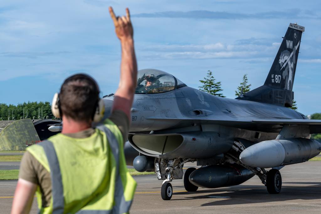 El capitán Eric Murray, piloto de F-16 Fighting Falcon del 14.º Escuadrón de Caza de la Fuerza Aérea de los Estados Unidos, responde con un gesto de la mano «Samurai Wood» a un aviador del 14.º Escuadrón de Caza de Generación durante el ejercicio Resolute Force Pacific 2025 en la base aérea de Misawa, Japón, el 23 de julio de 2025. El ejercicio valida la capacidad de las Fuerzas Aéreas del Pacífico para liderar operaciones de contingencia multinacionales a gran escala con más de 12 000 efectivos y 400 aeronaves movilizados. (Fotografía de la Fuerza Aérea de los Estados Unidos realizada por el aviador de primera clase Andre Medina).