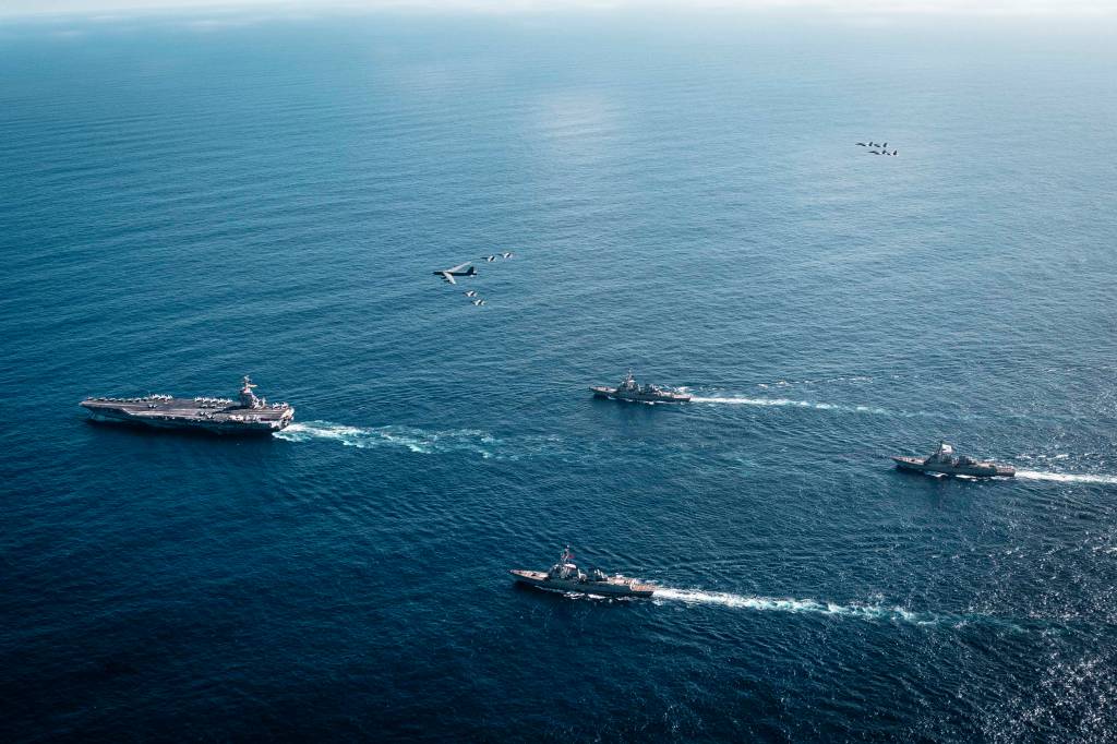 El Grupo de Ataque del Portaaviones Gerald R. Ford de la Marina de los Estados Unidos, que incluye el buque insignia USS Gerald R. Ford (CVN 78), a la izquierda, el USS Winston S. Churchill (DDG 81), al frente, el USS Mahan (DDG 72), atrás, el USS Bainbridge (DDG 96) y los Super Hornets F/A-18E/F del Ala Aérea 8 embarcados, asignados a los Escuadrones de Cazas de Ataque 31, 37, 87 y 213, opera como una fuerza conjunta y multidominio con un B-52 Stratofortress de la Fuerza Aérea de los Estados Unidos, el 13 de noviembre de 2025. Las fuerzas militares estadounidenses, como el Grupo de Ataque del Portaaviones Gerald R. Ford, se despliegan en apoyo de la misión del Comando Sur de los Estados Unidos, las operaciones dirigidas por el Departamento de Guerra y las prioridades del presidente para desarticular el tráfico ilícito de drogas y proteger el territorio nacional. ©US Navy