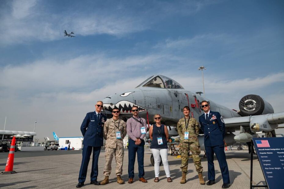 El teniente general Derek France, comandante de las Fuerzas Aéreas Centrales de los Estados Unidos, posa junto a miembros del servicio y civiles del Departamento de Guerra frente a un avión A-10 Thunderbolt, mientras un avión B-52 Stratofortress vuela al fondo en el Aeropuerto Internacional Al Maktoum, Dubái, el 17 de noviembre de 2025. Asistieron al Salón Aeronáutico Internacional de Dubái, un evento que refuerza los lazos entre las fuerzas estadounidenses y sus socios internacionales en materia de aviación y defensa nacional. (Fotografía de la Fuerza Aérea de los Estados Unidos realizada por el sargento técnico Justin Norton).