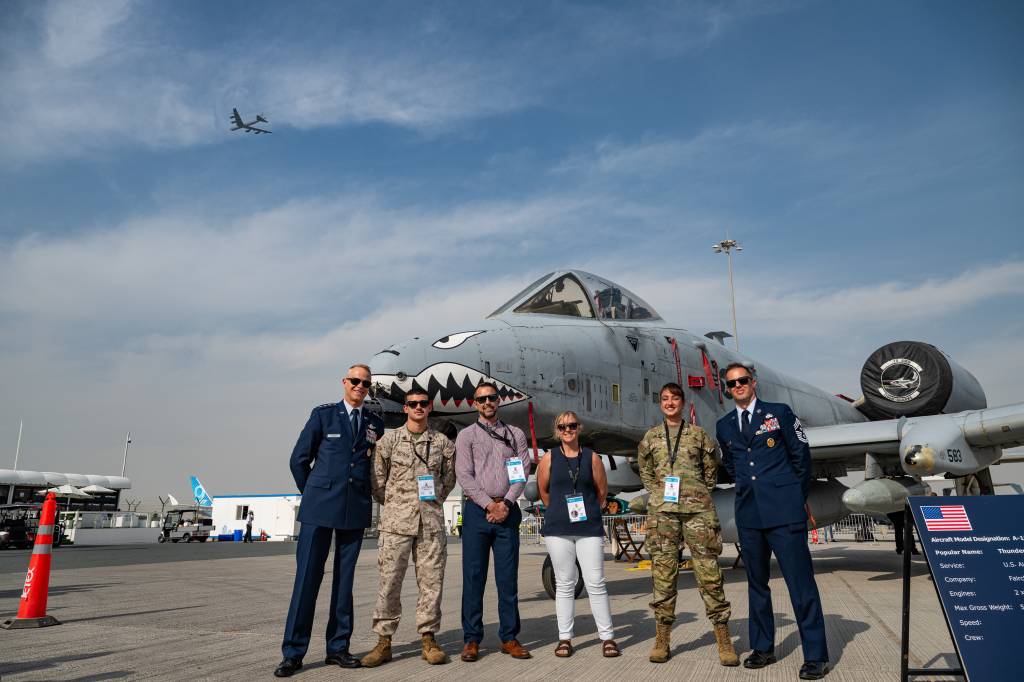 El teniente general Derek France, comandante de las Fuerzas Aéreas Centrales de los Estados Unidos, posa junto a miembros del servicio y civiles del Departamento de Guerra frente a un avión A-10 Thunderbolt, mientras un avión B-52 Stratofortress vuela al fondo en el Aeropuerto Internacional Al Maktoum, Dubái, el 17 de noviembre de 2025. Asistieron al Salón Aeronáutico Internacional de Dubái, un evento que refuerza los lazos entre las fuerzas estadounidenses y sus socios internacionales en materia de aviación y defensa nacional. (Fotografía de la Fuerza Aérea de los Estados Unidos realizada por el sargento técnico Justin Norton).
