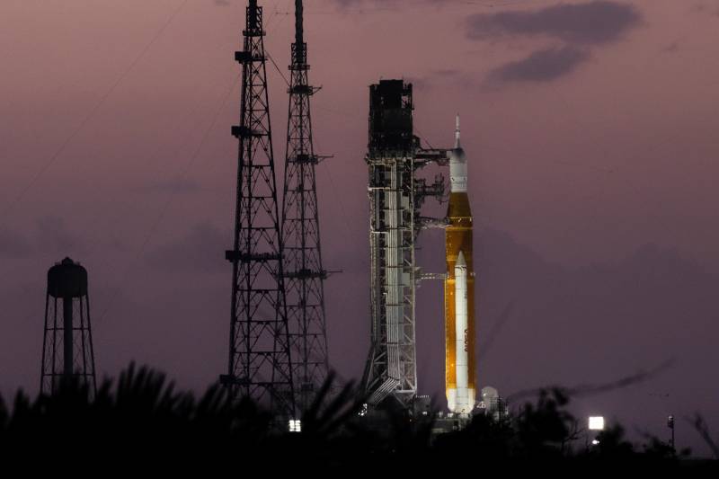 El sol sale detrás del cohete SLS (Sistema de Lanzamiento Espacial) de la misión Artemis II de la NASA y la nave espacial Orión, situados sobre una plataforma de lanzamiento móvil en el Complejo de Lanzamiento 39B del Centro Espacial Kennedy de la NASA, en Florida, el 30 de marzo de 2026. Crédito: NASA/Jim Ross