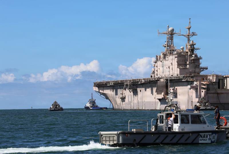 Cuatro remolcadores escoltan al casco del buque de asalto anfibio de la clase Tarawa USS Peleliu (LHA 5), ya fuera de servicio, a través de Pearl Harbor, Hawái, en preparación para un ejercicio combinado de hundimiento como parte del Ejercicio Rim of the Pacific 2026, el 15 de julio de 2026. Durante más de 35 años de servicio naval, el Peleliu, con un desplazamiento de casi 40 000 toneladas, lanzó una gran variedad de aeronaves desde su formidable cubierta de vuelo mientras llevaba a cabo operaciones de combate y misiones humanitarias por medio mundo. Los LHA son los buques de guerra anfibios más grandes que existen y se asemejan a un pequeño portaaviones. Treinta naciones, 30 buques, cinco submarinos, 15 fuerzas terrestres nacionales, más de 190 aeronaves y más de 30 000 efectivos participan en el RIMPAC en las islas de Hawái y sus alrededores, del 24 de junio al 31 de julio. El RIMPAC, el ejercicio marítimo internacional más grande del mundo, ofrece una oportunidad única de entrenamiento al tiempo que fomenta y mantiene relaciones de cooperación entre los participantes, fundamentales para garantizar la seguridad de las rutas marítimas y la seguridad en los océanos del mundo. El RIMPAC 2026 es el trigésimo ejercicio de la serie que comenzó en 1971. (Foto de la Armada de EE. UU. tomada por el marinero Nathan Cahall, especialista en comunicaciones masivas)
