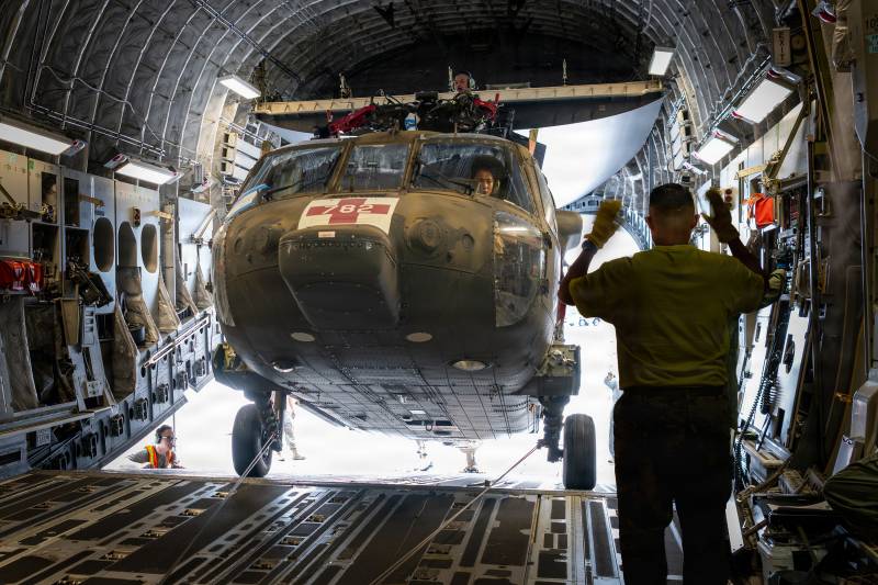 El suboficial de cuarto grado del Ejército de los EE. UU. Hau Okada, piloto de la Guardia Nacional del Ejército de Hawái, maniobra un helicóptero UH-60M Black Hawk a bordo de un C-17 Globemaster III de la Guardia Aérea Nacional de Hawái, asignado al 204.º Escuadrón de Transporte Aéreo, mientras el sargento primero del Ejército de los EE. UU. Christopher Pacheco, mecánico principal e instructor de estandarización de la Guardia Nacional del Ejército de Hawái, guía la aeronave desde lo alto de su sistema de rotor plegado durante las operaciones de carga en el Aeropuerto Internacional de Hilo, el 31 de julio de 2026. La carga requirió una estrecha coordinación entre pilotos, personal de mantenimiento, guías de tierra y jefes de carga para preparar de manera segura la aeronave para su transporte a la Base Aérea Clark, en Filipinas, lo que marcó el primer despliegue de un Black Hawk de la Guardia Nacional del Ejército de Hawái a Filipinas para entrenamiento aéreo bilateral en el marco del Programa de Asociación Estatal de la Oficina de la Guardia Nacional del Departamento de Guerra entre Hawái y Filipinas. Foto de la sargento mayor Mysti Bicoy.